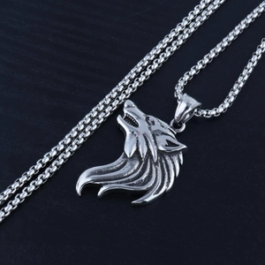 Detail of vintage silver wolf head pendant with thick box chain on dark wood background