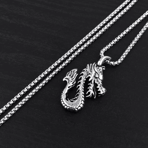 Vintage stainless steel dragon pendant necklace with detailed scales on black wood background