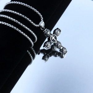 Detail view of vintage stainless steel cross pendant with intricate 3D engravings and chain