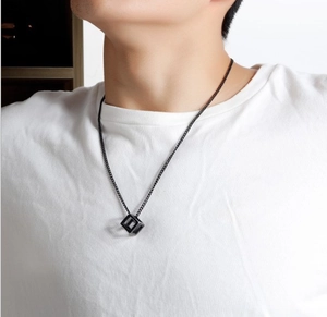 Close-up of minimalist black hollow cube pendant necklace on a white t-shirt