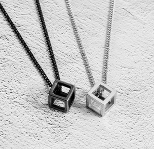 Close-up of minimalist hollow cube pendants in matte black and silver finishes