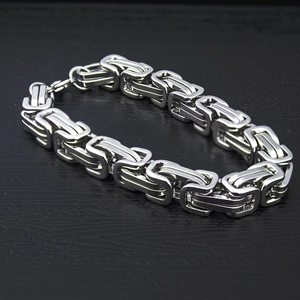 Macro shot of silver Byzantine chain bracelet in polished stainless steel on wood