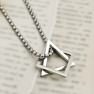 Close-up of geometric triangle and square pendant on a silver box chain necklace