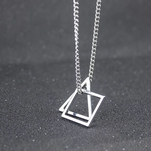 Collier argenté avec pendentifs géométriques carré et triangle sur fond texturé sombre