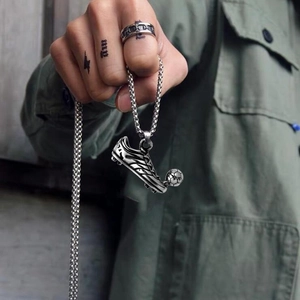 Close-up of a silver-tone soccer cleat and ball pendant on a thick metal link chain