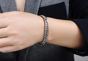 Macro shot of silver stainless steel Cuban link bracelet worn with a dark grey suit