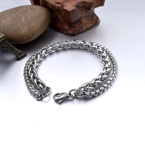 Detail of silver wheat-patterned chain bracelet with lobster clasp on textured surface