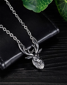Macro shot of vintage silver stag head pendant necklace on a dark textured background