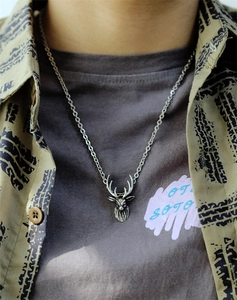 Detail view of retro silver reindeer antler pendant necklace worn on a casual outfit