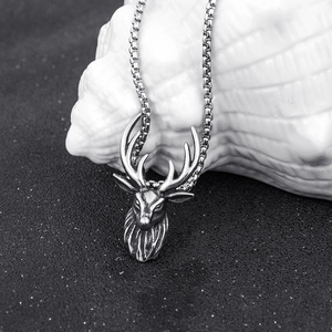 Detailed macro shot of vintage stag head pendant with intricate antler textures on black sand