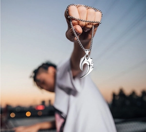 Détail d'un pendentif griffe argenté avec cristal central sur une chaîne à billes