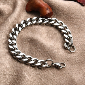 Polished silver cuban link chain bracelet on silk fabric with a secure lobster clasp