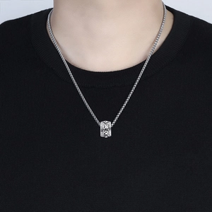 Detail of vintage silver cylinder pendant necklace with engraved Buddhist symbols on model