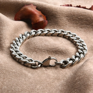 Polished silver Cuban link bracelet with lobster clasp on natural linen fabric