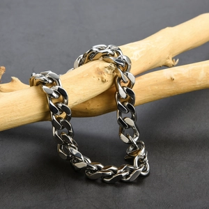 Close-up of thick silver Cuban curb chain wrapped on wood, showing polished steel texture