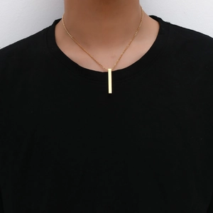 Primo piano di una collana alla moda con pendente a barra dorata indossata da una modella