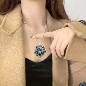 Detail of vintage silver wolf head necklace worn by male model over brown coat