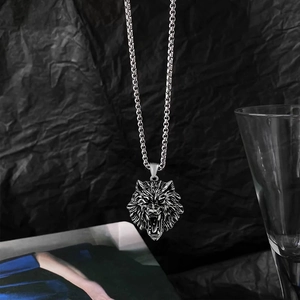 Detailed shot of a silver wolf head pendant necklace on a textured black background