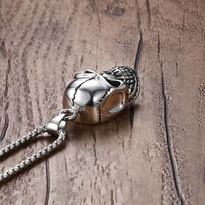 Detailed macro view of vintage silver skull pendant on steel box chain over wood