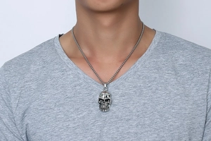 Detailed close-up of a large punk skull pendant with box chain on a male model