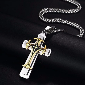 Gros plan sur un pendentif croix multicouche en acier inoxydable avec détails gravés fins
