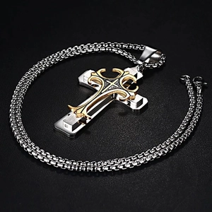 Détail macro du pendentif croix étagé en or et argent avec motifs gravés baroques