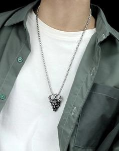 Detail view of retro silver demon pendant necklace on male model with layered clothing
