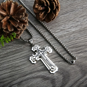 Vue détaillée d'un pendentif croix en acier inoxydable argenté sur un fond en bois sombre