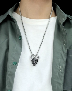 Macro shot of vintage silver devil head necklace on a male model with a thick round link chain