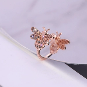 Adjustable rose gold bee ring with sparkling purple zircon crystals on reflective surface