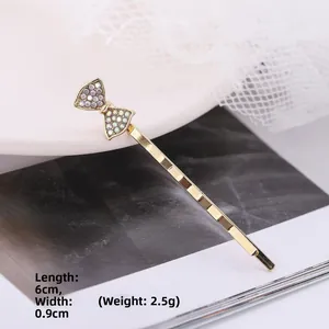 Dettaglio del fermaglio per capelli dorato con fiocco e strass lucidi da 6cm di lunghezza