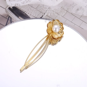 Barrette fleur dorée élégante avec perle centrale sur un support réfléchissant