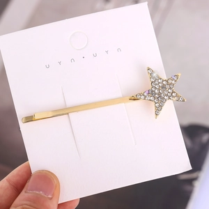 Minimalist gold star hair clip with white rhinestones on white display card