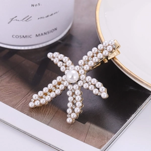 Zeester haarklem met witte parels en strass op goud metaal in een lifestyle setting