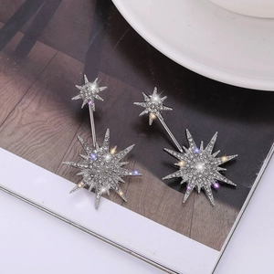 Sparkling S925 silver snowflake earrings with clear crystals shown on a magazine background