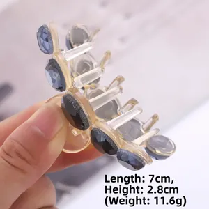 Detail view of a 7cm crystal hair claw clip with measurements on a hand