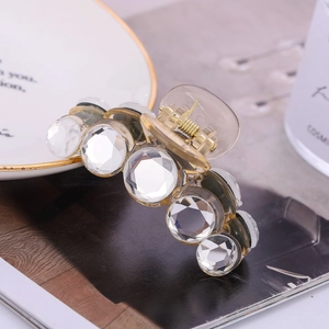 Close-up of sparkling faceted crystals and golden metal spring on acrylic hair claw clip