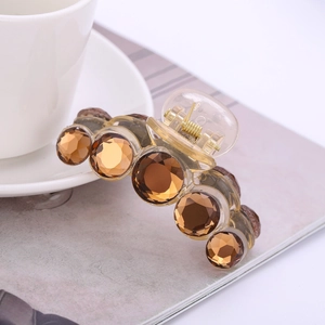 Elegant champagne crystal hair claw clip with amber rhinestones on a magazine background