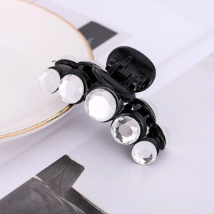 Detail of a black acrylic hair claw clip decorated with five sparkling white crystals