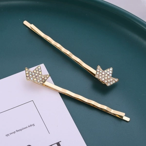Set de barrettes couronne dorées élégantes avec strass brillants sur plateau vert