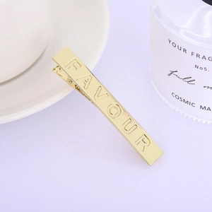 Gedetailleerde weergave van een gouden haarclip met gegraveerde FAVOUR belettering