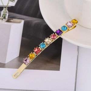 Fermaglio per capelli dorato con strass multicolori su tazza e sfondo di rivista