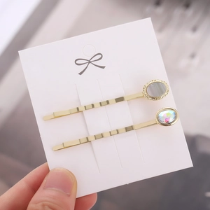 Minimalistisches goldenes Haarklammern-Set mit ovalen Edelsteinen auf Display-Karte