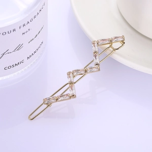 Elegante fermaglio per capelli a forma di S dorato con cristalli scintillanti su piano bianco