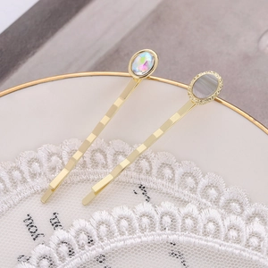 Minimalistische goldene Haarklammern mit bunten Strasssteinen und grauer Muschel