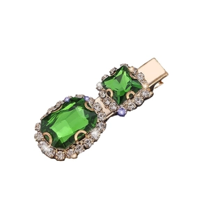 Retro hair clip with large green gemstones and white rhinestones on a gold base