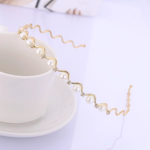 Serre-tête vague doré élégant orné de perles blanches et strass sur une tasse à café