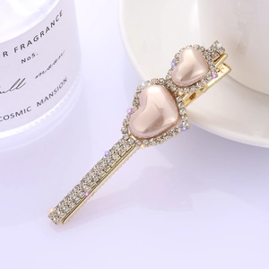 Elegante molletta dorata con due cuori rosa perlati e intarsio di strass scintillanti