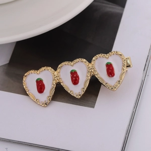 Pince à cheveux dorée en forme de cœur avec émail blanc et breloques fraise