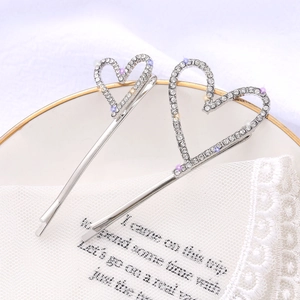 Baroque silver heart hair clips with pavé crystals on white lace and ceramic tray